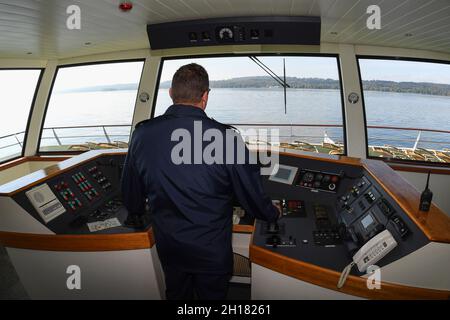 Starnberg, Deutschland. Oktober 2021. Martin Neumann, Kapitän auf der MS Starnberg, steuert den Katamaran über den Starnberger See. Heute ist der letzte Tag der Schifffahrt auf dem Starnberger See in diesem Jahr. Quelle: Felix Hörhager/dpa/Alamy Live News Stockfoto