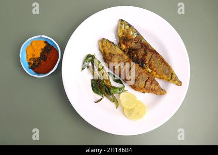 Indische Makrelenfischbraten. Bangda Rava Fry. Gebratener Fisch auf einem Bananenblatt mit gebratenen Chilischoten, Zitronenscheiben und indischen Gewürzen. Stockfoto