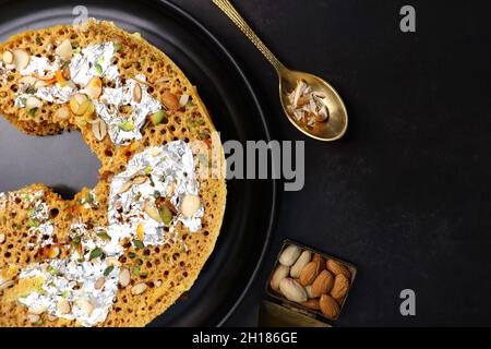 Rajasthani Ghevar. Ghewar ist ein indisches knusprig-süßes Gericht, das aus raffiniertem Mehl, Zucker und Ghee hergestellt wird. Göttin Laxmi Idol. Stockfoto