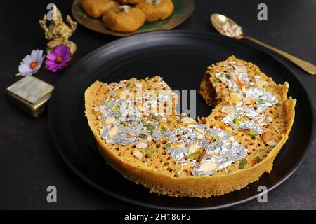 Rajasthani Ghevar. Ghewar ist ein indisches knusprig-süßes Gericht, das aus raffiniertem Mehl, Zucker und Ghee hergestellt wird. Göttin Laxmi Idol. Stockfoto