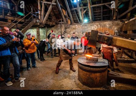 17. Oktober 2021, Sachsen, Olbernhau: Der handwerkliche Schmied Thore Krauter zeigt seinen Besuchern sein Handwerk bei einer Schauschmiede im Kupferhammer in der Saigerhütte. Am 22. Tag des traditionellen Handwerks im Erzgebirge öffnen zahlreiche Handwerksbetriebe aus verschiedenen Branchen ihre Türen. Foto: Kristin Schmidt/dpa-Zentralbild/ZB Stockfoto