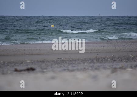 Verschiedene Schwerpunkte eines Strandes gegen das Meer mit einer kleinen schwimmenden Boje Stockfoto