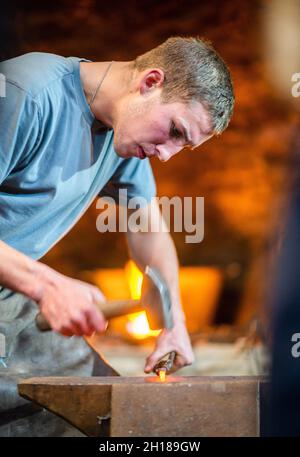 17. Oktober 2021, Sachsen, Olbernhau: Der handwerkliche Schmied Thore Krauter zeigt seinen Besuchern sein Handwerk bei einer Schauschmiede im Kupferhammer in der Saigerhütte. Am 22. Tag des traditionellen Handwerks im Erzgebirge öffnen zahlreiche Handwerksbetriebe aus verschiedenen Branchen ihre Türen. Foto: Kristin Schmidt/dpa-Zentralbild/ZB Stockfoto