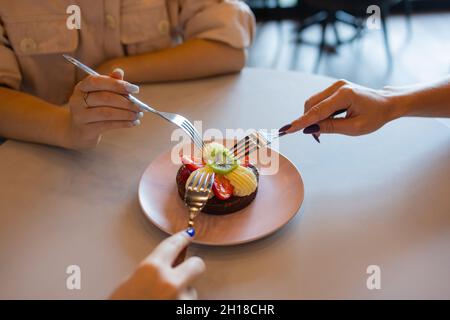 Schokoladen-Muffins mit Erdbeeren und weißer Creme auf einem Holztisch Stockfoto
