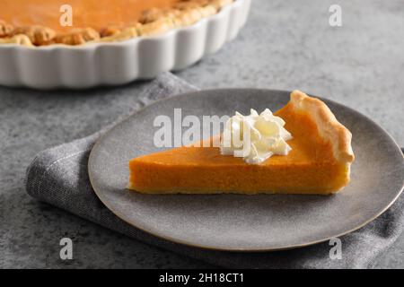 Stück des traditionellen American Pumpkin Pie in Teller auf grauem Stein Hintergrund. Nahaufnahme. Hausgemachtes Gebäck für Thanksgiving Day. Stockfoto