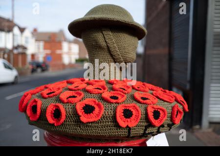 New Brighton UK Oktober 2021 Red Poppy Fund Raiser Royal british Legion Appeal auf roten Briefkästen mit gestricktem tommy und Helm Stockfoto