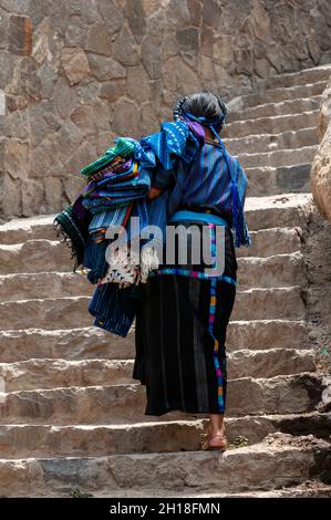 Eine Frau in traditioneller Kleidung, die steile Steintreppen klettert. San Antonio Palopo, Solola, Guatemala. Stockfoto