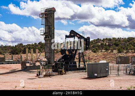 Eine langhubige Riemenpumpe und ein traditioneller Pumpenheber an benachbarten Ölquellen im Canyon-Land von Utah. Stockfoto