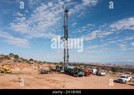 Eine Zieheinheit oder ein Überarbeitungs-Rig an einer Ölbohrstelle in Utah. Dahinter stehen die Monitor & Merrimac Buttes & Book Cliffs. Stockfoto