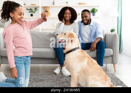 Happy black girl giving treat to her labrador Stockfoto