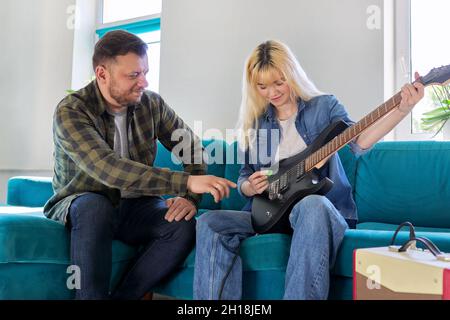 Vater lehrt Teenager-Tochter, die E-Gitarre zu spielen. Stockfoto