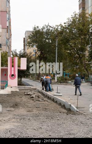 Tiraspol, Moldawien - 15. Oktober 2021: Straßendienstmitarbeiter installieren neue Betonkanten im Innenhof eines Mehrfamilienhauses in der Hauptstadt der Republik Moldau Stockfoto