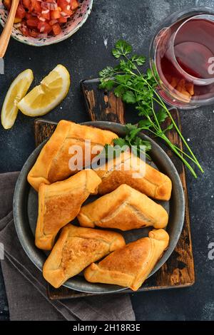 Gebratene Empanadas mit Koriander, Fleisch, Ei, Tomaten und Chilisauce auf schwarzem Hintergrund. Typisch chilenisches Gericht. Lateinamerikanische und chilenische Unabhängigkeit da Stockfoto