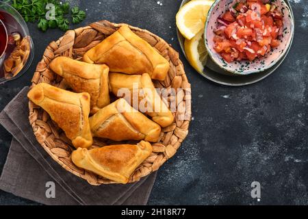 Gebratene Empanadas mit Koriander, Fleisch, Ei, Tomaten und Chilisauce auf schwarzem Hintergrund. Typisch chilenisches Gericht. Lateinamerikanische und chilenische Unabhängigkeit da Stockfoto