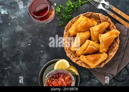 Gebratene Empanadas mit Koriander, Fleisch, Ei, Tomaten und Chilisauce auf schwarzem Hintergrund. Typisch chilenisches Gericht. Lateinamerikanische und chilenische Unabhängigkeit da Stockfoto