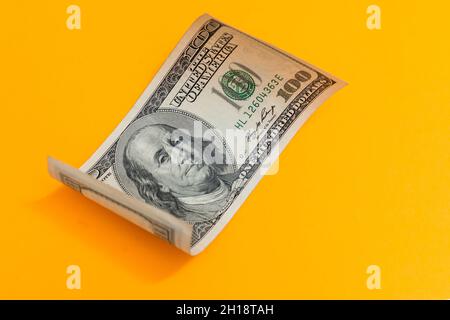 Einhundert-Dollar-Bill rollte auf Gelb Stockfoto