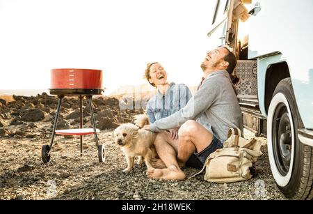 Hipster-Paar mit niedlichem Hund, der zusammen auf Oldtimer-Minivan-Transport reist - Reise-Lebensstilkonzept mit Indie-Leuten auf Minivan Stockfoto