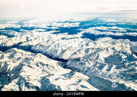 Luftaufnahme der italienischen Alpen mit Schnee und nebligen Horizont - Reisekonzept und Winterurlaub auf weißen schneebedeckten Bergen Stockfoto