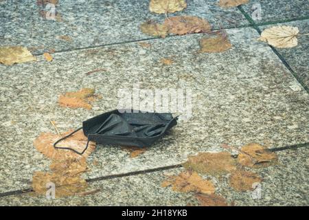 Alte gebrauchte Einweg-Gesichtsmaske fiel auf Bürgersteig in der Stadt Stockfoto