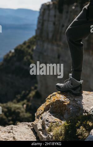 Wanderschuh einer Frau, die an einem sonnigen Tag auf einen kleinen Felsen mit Bergrücken tritt. Speicherplatz kopieren. Stockfoto