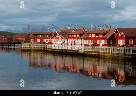 Hell gestrichene, sonnendurchflutete Gebäude im Fischerdorf Svolvaer spiegeln die Hafengewässer wider. Svolvaer, Austvagoya Island, Lofoten, Norwegen. Stockfoto