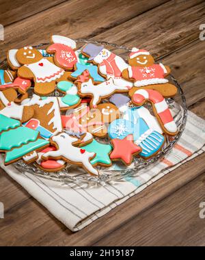 Hell und bunt dekorierte Lebkuchen Weihnachtsplätzchen auf einem Teller mit einem hölzernen Hintergrund. Stockfoto