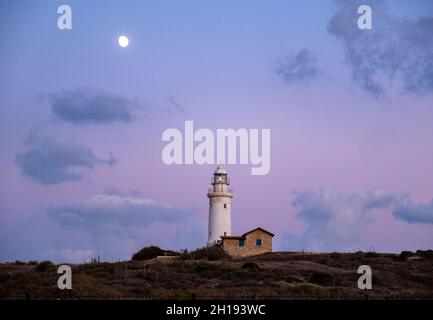 Der Mond steigt hinter dem Leuchtturm von Paphos, Paphos Point, Zypern. Stockfoto