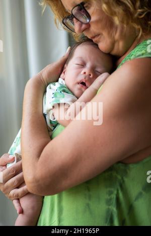 Großmutter hält schlafend 40 Tage alten neugeborenen Jungen am Fenster zu Hause Stockfoto