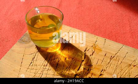 Voll mit Linden gefüllte Glaskanne auf Holzplatte und rotem Teppich Stockfoto