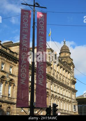 Der Werbeslogan „People Make Glasgow“ steht auf Transparenten am George Square in Glasgow, einem Markennamen, der Schottlands größte Stadt vermarktet. Stockfoto