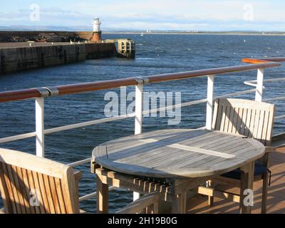 Kreuzfahrt auf den Western Isles: Tisch und Stühle am Geländer an Deck auf dem Kreuzschiff MS Island Sky im Hafen von Troon, Westküste Schottlands. Stockfoto