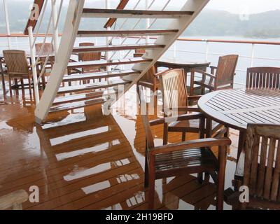 Kreuzfahrt im Oktober an Schottlands Westküste: Seien Sie auf schlechtes Wetter vorbereitet, da dieses Foto von dem sehr nassen Tisch und Stühlen auf dem Sonnendeck. Stockfoto