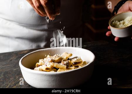 Der Koch legt Käse auf Pasta Stockfoto