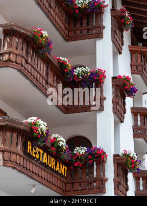 Traditionelle alpine Holzbalkone eines Restaurants, mit Blumen geschmückt, besonders typisch für die deutsche Schweiz und Tirol. Samnaun, Schweiz, Stockfoto