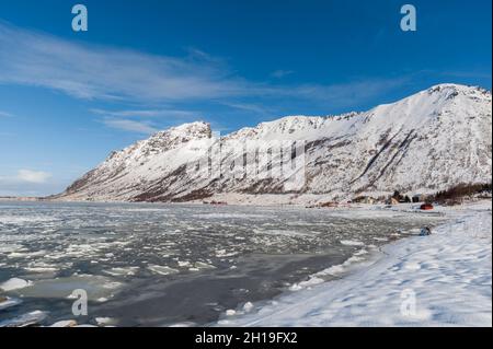 Schneebedeckte Berge und Eispickeln in der Bucht von Knutstad. Knutstad, Lofoten Islands, Nordland, Norwegen. Stockfoto