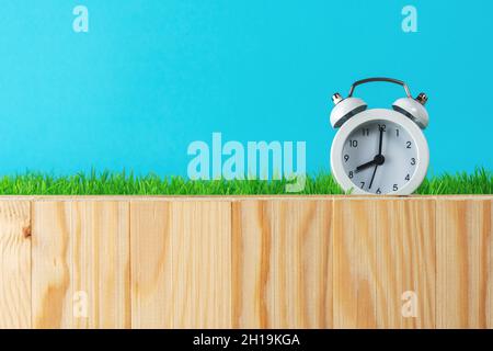 Kreative Komposition mit Wecker auf Holztisch. Minimaler Osterhintergrund. Konzept der Frühlingsferien. Stockfoto