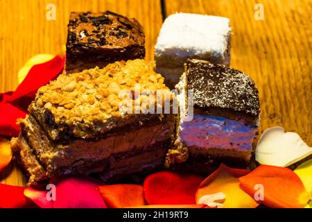 Eine Nahaufnahme einer Mischung aus Rosenblüten und Kuchen, die auf einem rustikalen Holztisch aufgestellt wurde Stockfoto