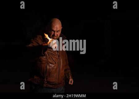 Der kahlköpfige Kaukasusmann schlägt mit brennender Faust. Stockfoto