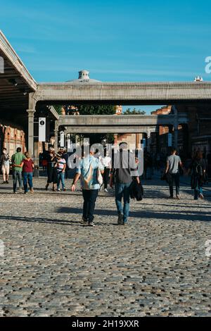 MADRID, SPANIEN - 26. Sep 2021: Menschen, die entlang der mit Pflastersteinen bedeckten Straße zu einem Kunstzentrum Matadero im Arganzuela-Viertel von M gehen Stockfoto