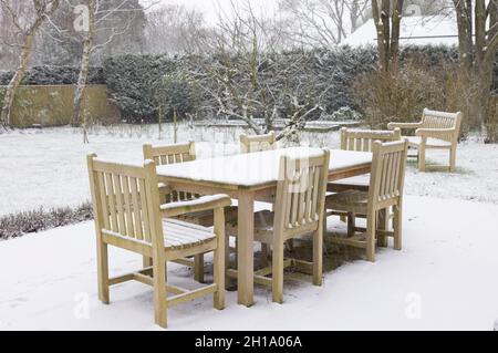 Terrasse Gartenmöbel, Holztisch und Stühle mit Schnee im Winter bedeckt, Großbritannien Stockfoto