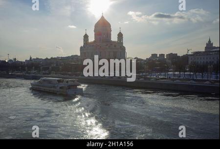 17. März 2018, Moskau, Russland. Ein Ausflugsboot auf dem Moskauer Fluss vor dem Hintergrund der Kathedrale von Christus dem Erlöser im Abendlicht. Stockfoto