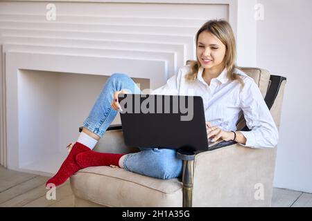 Lächelnde Frau mit Laptop macht Telearbeit in der Lounge. Stockfoto