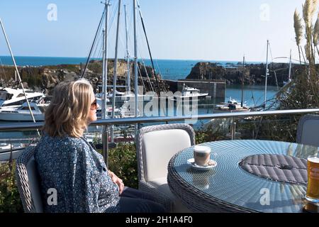 dh Beaucette Marina VAL GUERNSEY Frau Touristencafe mit Blick auf Yachten in Hafen Yachthäfen Boote Hafen Menschen Stockfoto