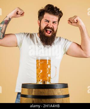 Aufgeregter bärtiger Mann mit Lagerbier. Bierkneipe und Bar. Mann mit Becher Getränk. Fröhlicher Brauer mit einem Glas Ale Stockfoto