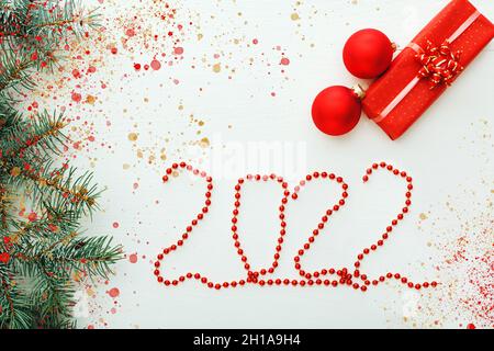 2022 Grußkarte mit Dekorationen. Happy New Year Weihnachtskomposition Karte mit Geschenken Geschenkboxen auf weißem Holztisch. Festliche Grußkarte Stockfoto