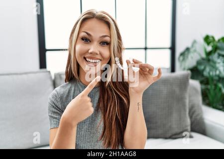 Junge kaukasische Frau mit unsichtbarem Ausrichter kieferorthopädisch lächelnd glücklich zeigt mit Hand und Finger Stockfoto