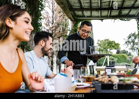 Eine Gruppe lateinamerikanischer Freunde, die in einem mexikanischen Restaurant oder einer Bar Tacos aßen, die von Kellnern in Mexiko, lateinamerika besucht wurden Stockfoto