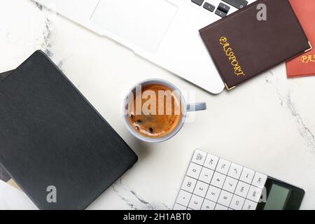 Komposition mit Tasse Kaffee, Reisepass, Taschenrechner und Notizbuch auf hellem Hintergrund Stockfoto