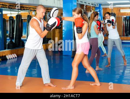 Junge Frau in Boxhandschuhen, die auf Fokushandschuhe schlagen Stockfoto