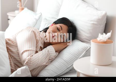 Reife Frau mit rosa Ohrstöpsel schlafen im Bett Stockfoto